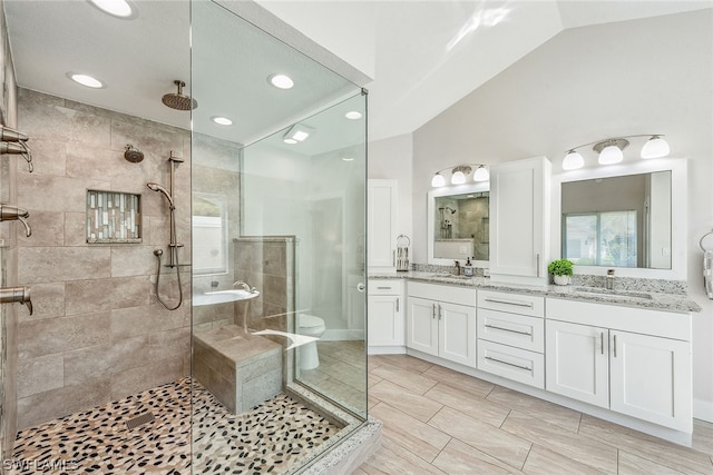 full bathroom featuring separate shower and tub, tile floors, vaulted ceiling, large vanity, and toilet