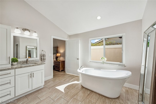 bathroom with tile flooring, a tub, vaulted ceiling, and vanity with extensive cabinet space