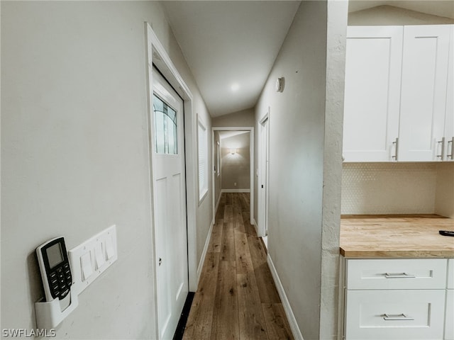 hallway with vaulted ceiling and wood-type flooring