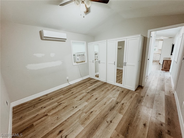 unfurnished bedroom featuring vaulted ceiling, ceiling fan, light hardwood / wood-style floors, and a wall mounted AC