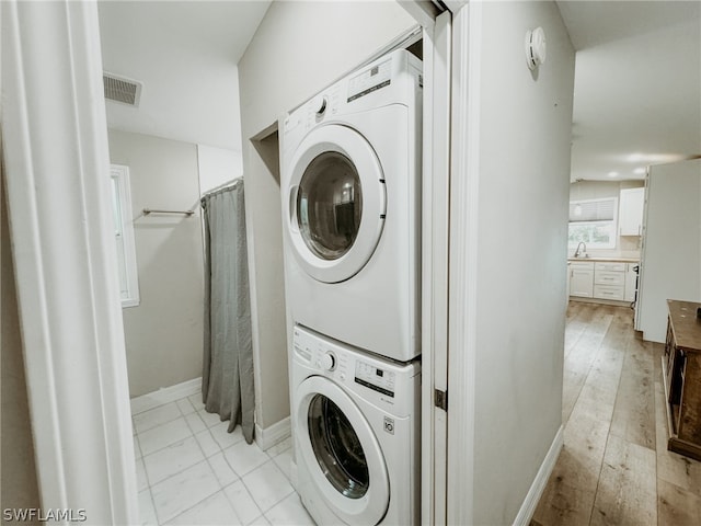 washroom featuring stacked washer and clothes dryer and light tile floors