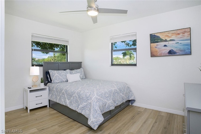 bedroom with ceiling fan, multiple windows, and light hardwood / wood-style flooring