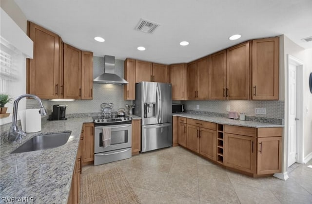 kitchen with wall chimney range hood, stainless steel appliances, backsplash, sink, and light tile floors