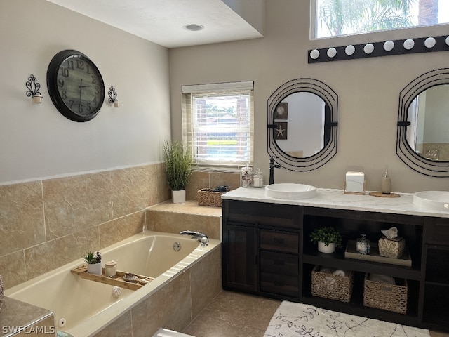 bathroom with a healthy amount of sunlight, a relaxing tiled bath, double sink vanity, and tile floors