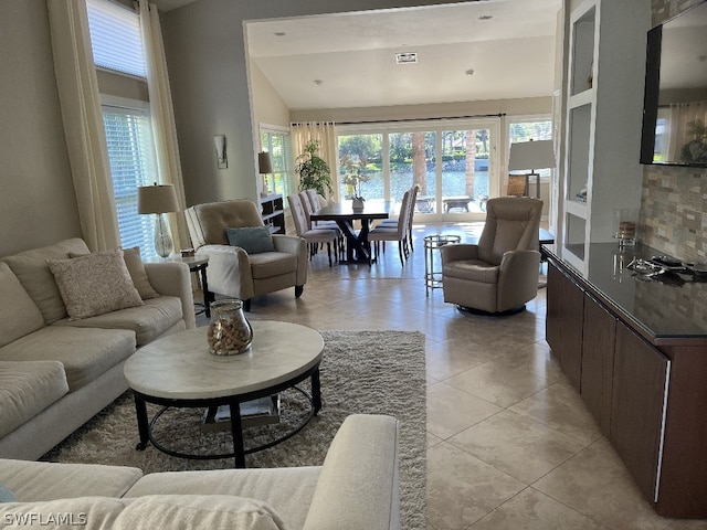 living room with lofted ceiling, light tile flooring, and a water view