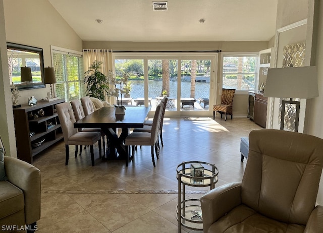 tiled dining space with a water view and lofted ceiling