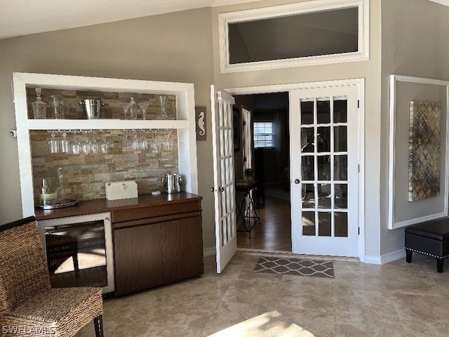 interior space with vaulted ceiling, beverage cooler, french doors, and light tile floors