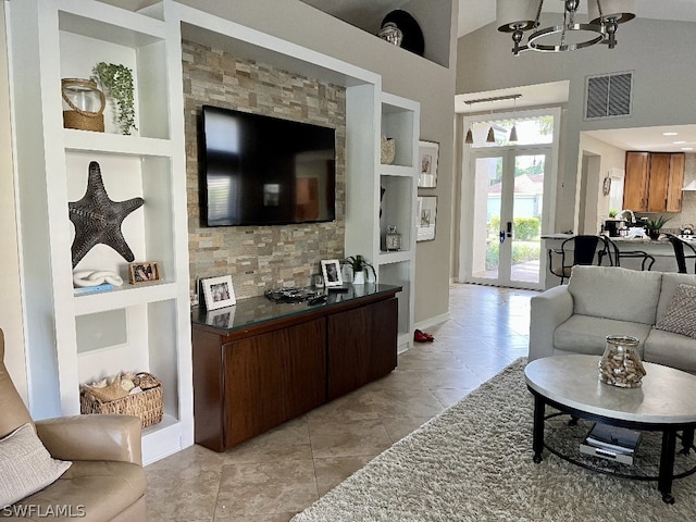 living room with french doors, built in features, a notable chandelier, light tile floors, and high vaulted ceiling