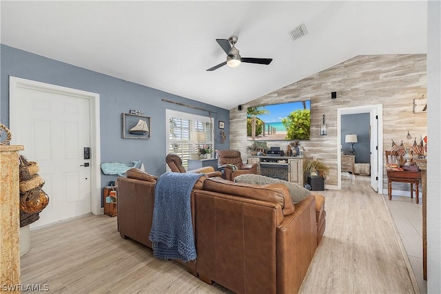 living room with lofted ceiling, light hardwood / wood-style floors, ceiling fan, and wooden walls