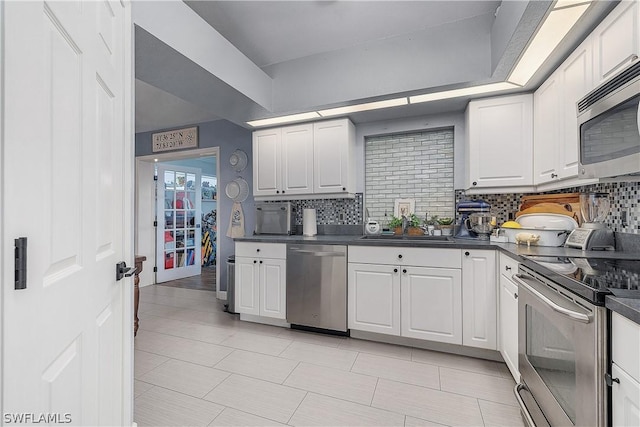 kitchen with white cabinets, sink, backsplash, and appliances with stainless steel finishes