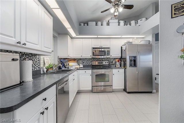 kitchen with sink, backsplash, lofted ceiling, white cabinets, and appliances with stainless steel finishes