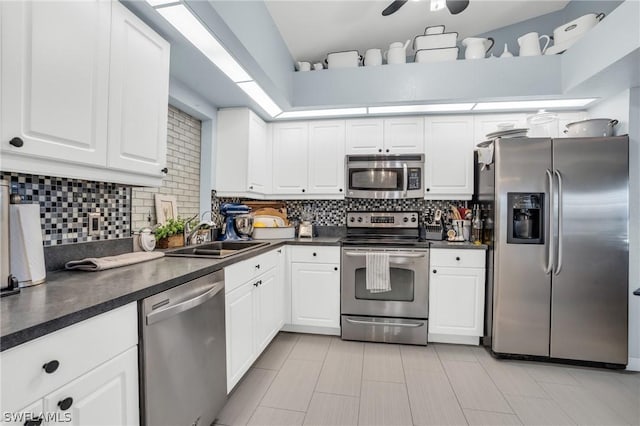 kitchen with tasteful backsplash, sink, white cabinets, and appliances with stainless steel finishes