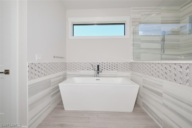 bathroom featuring a tub, tile walls, and tile floors