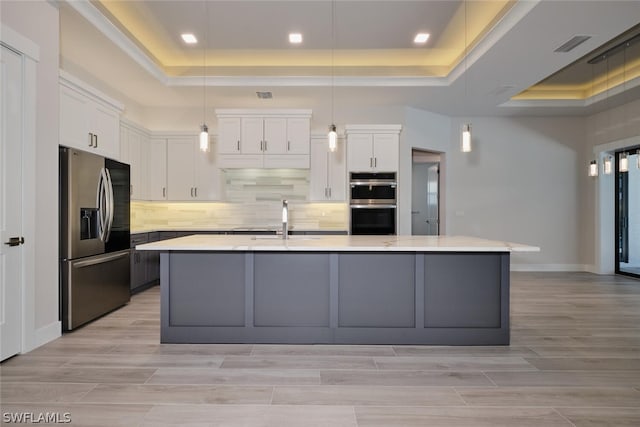 kitchen with a raised ceiling, stainless steel appliances, sink, and white cabinetry