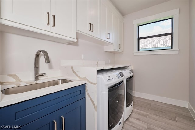 washroom with separate washer and dryer, sink, light hardwood / wood-style flooring, and cabinets