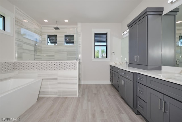 bathroom with double vanity and separate shower and tub