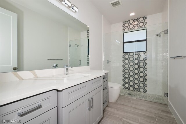 bathroom featuring tiled shower, vanity, and toilet