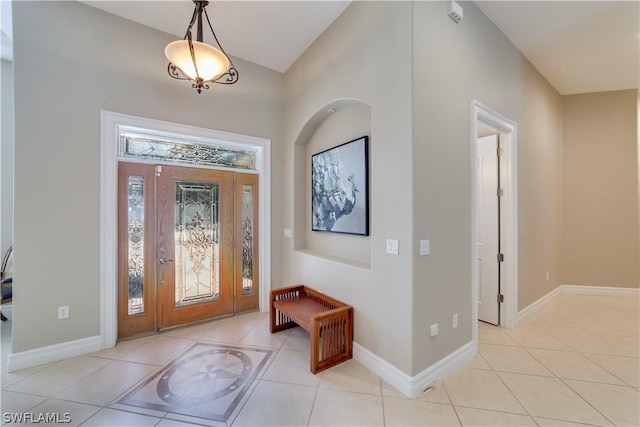 foyer featuring light tile patterned floors, baseboards, and vaulted ceiling