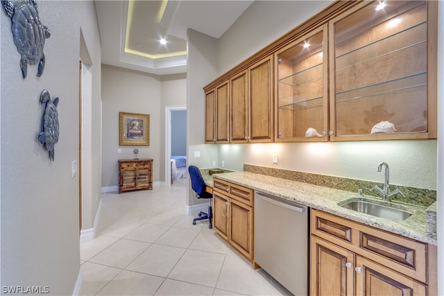 kitchen featuring dishwasher, a tray ceiling, light stone countertops, sink, and light tile floors