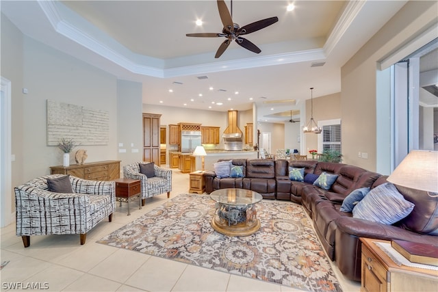 living room with ceiling fan, a tray ceiling, light tile flooring, and ornamental molding