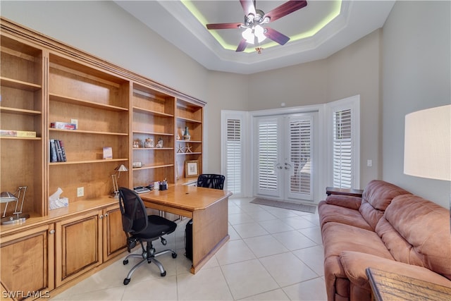 office space with a raised ceiling, ceiling fan, french doors, and light tile floors