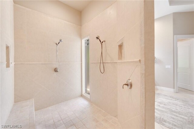 bathroom with tiled shower and tile flooring