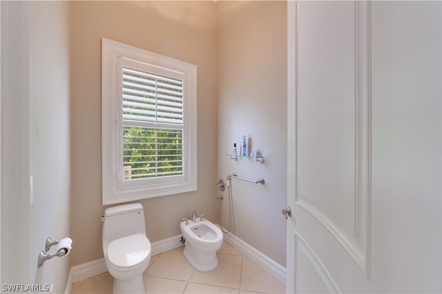 bathroom with a bidet, toilet, and tile floors