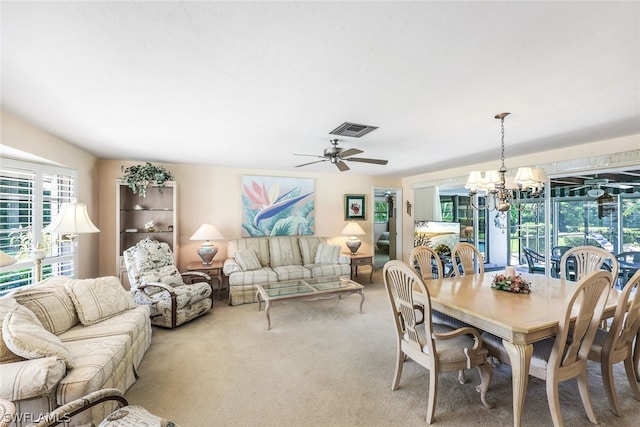 carpeted dining area featuring ceiling fan with notable chandelier