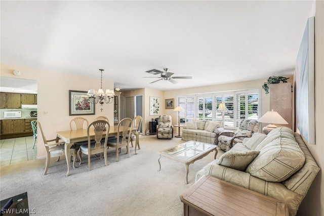 carpeted living room with ceiling fan with notable chandelier