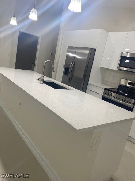 kitchen featuring white cabinetry, sink, hanging light fixtures, an island with sink, and appliances with stainless steel finishes