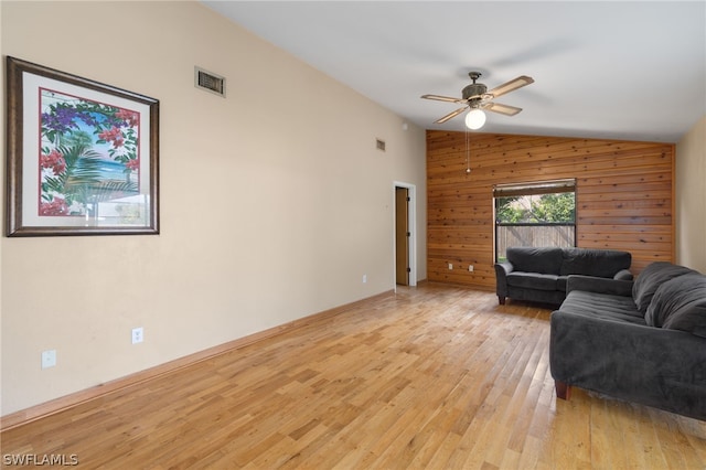 living room with vaulted ceiling, ceiling fan, light hardwood / wood-style floors, and wood walls