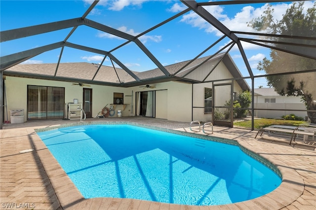 view of swimming pool featuring glass enclosure, a patio area, and ceiling fan