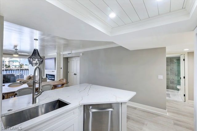 kitchen featuring light stone counters, a large fireplace, light hardwood / wood-style flooring, sink, and pendant lighting