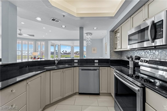 kitchen with sink, light tile patterned floors, gray cabinets, appliances with stainless steel finishes, and dark stone countertops