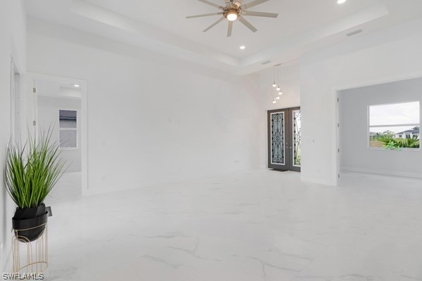 tiled living room featuring ceiling fan and a raised ceiling