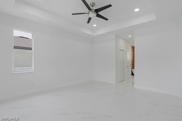 spare room featuring light tile patterned floors, a raised ceiling, and ceiling fan