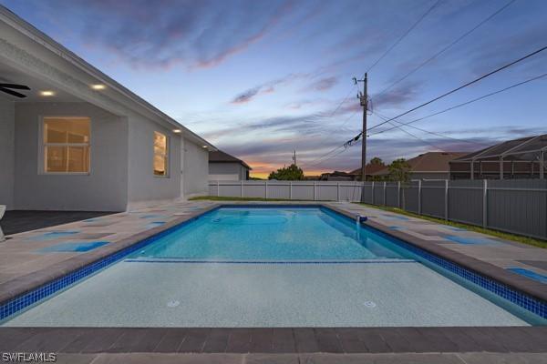 pool at dusk with a patio area