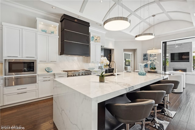 kitchen featuring vaulted ceiling, sink, a center island with sink, and white cabinets