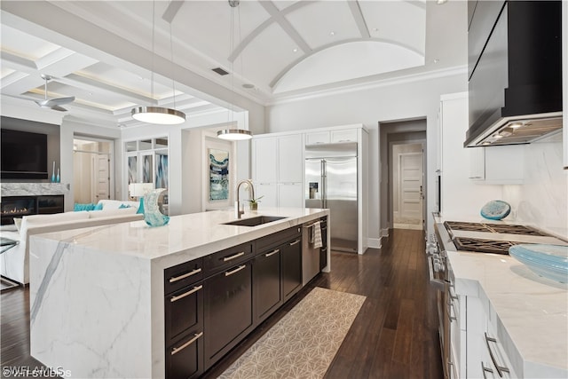 kitchen featuring pendant lighting, an island with sink, sink, premium appliances, and light stone counters