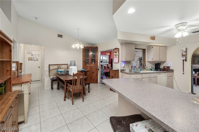 kitchen with white dishwasher, light tile flooring, vaulted ceiling, and ceiling fan with notable chandelier