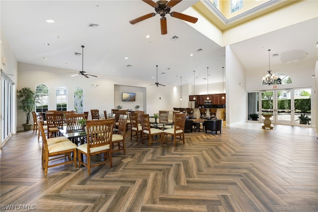 dining space featuring dark parquet flooring, ceiling fan with notable chandelier, high vaulted ceiling, and french doors