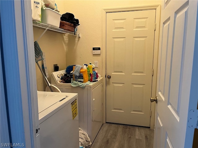 clothes washing area featuring electric dryer hookup, hardwood / wood-style flooring, and independent washer and dryer