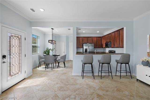 kitchen featuring pendant lighting, a kitchen breakfast bar, ornamental molding, and appliances with stainless steel finishes