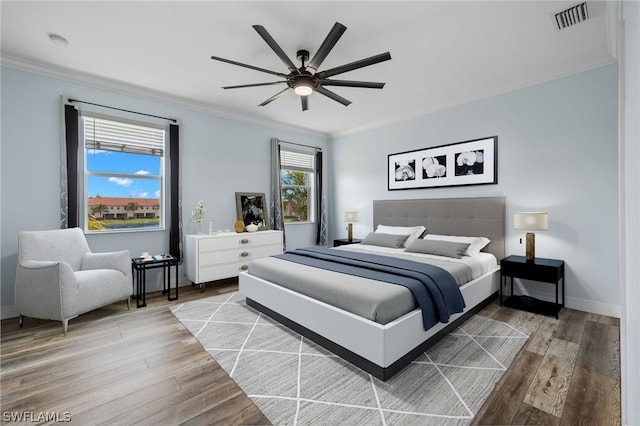 bedroom with hardwood / wood-style floors, ceiling fan, and ornamental molding