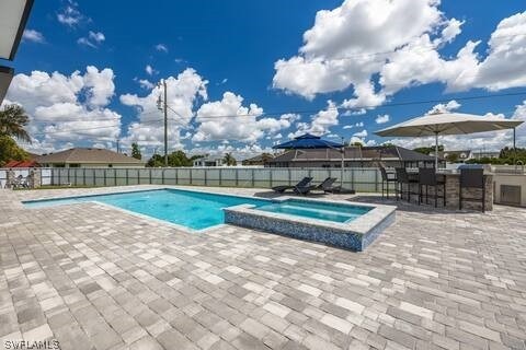 view of swimming pool with a patio, an in ground hot tub, and an outdoor bar