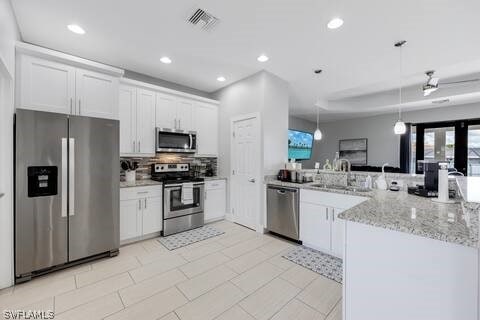 kitchen with pendant lighting, stainless steel appliances, white cabinets, and kitchen peninsula