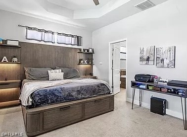 bedroom with ceiling fan, a raised ceiling, and ensuite bathroom