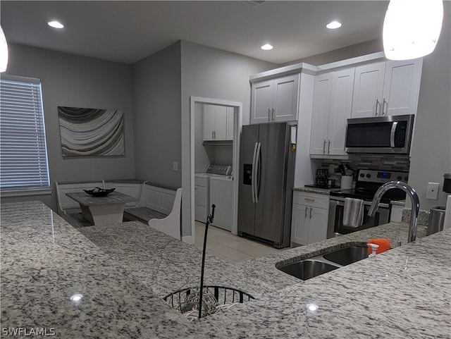 kitchen with light stone counters, separate washer and dryer, stainless steel appliances, and white cabinets