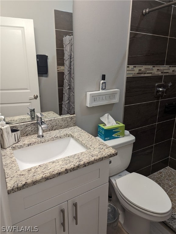 bathroom with curtained shower, vanity, and toilet