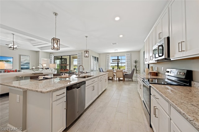 kitchen with stainless steel appliances, an island with sink, white cabinets, pendant lighting, and sink